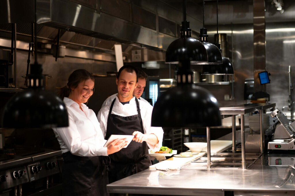 Två personer som står och diskuterar och antecknar i ett restaurangkök